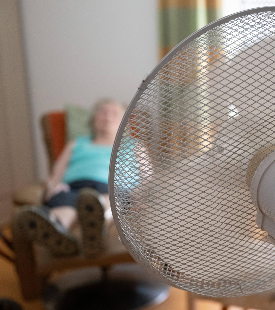 02.07.2025, Sachsen, Dresden: Die Bewohnerin eines Seniorenzentrums sitzt in ihrem Zimmer hinter einem Ventilator in einem Sessel.