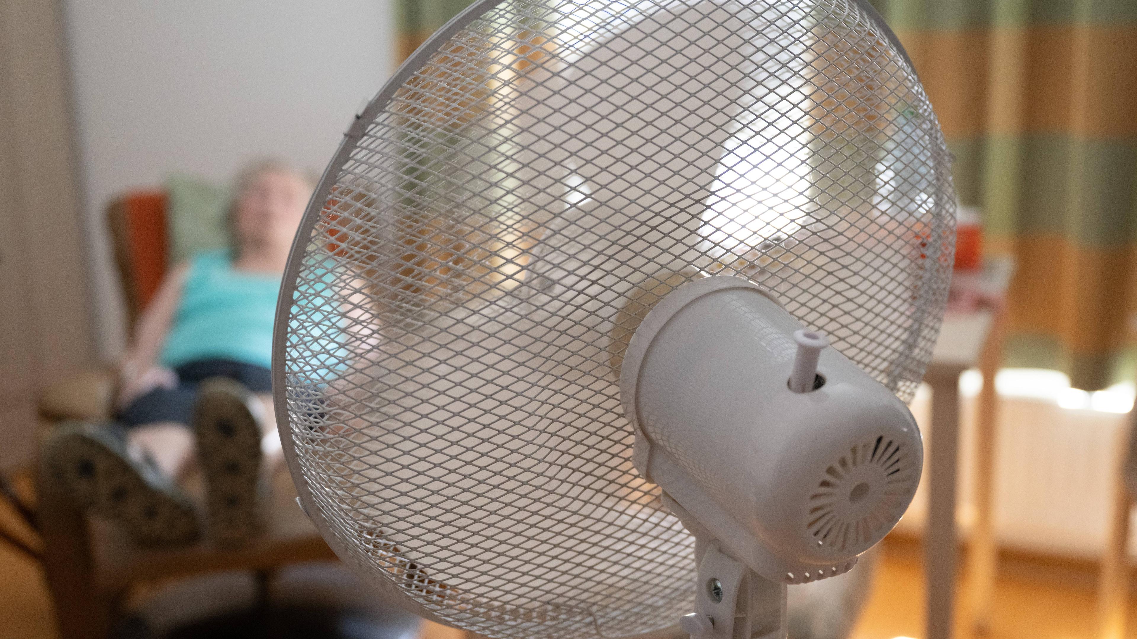 02.07.2025, Sachsen, Dresden: Die Bewohnerin eines Seniorenzentrums sitzt in ihrem Zimmer hinter einem Ventilator in einem Sessel.
