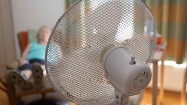 02.07.2025, Sachsen, Dresden: Die Bewohnerin eines Seniorenzentrums sitzt in ihrem Zimmer hinter einem Ventilator in einem Sessel.