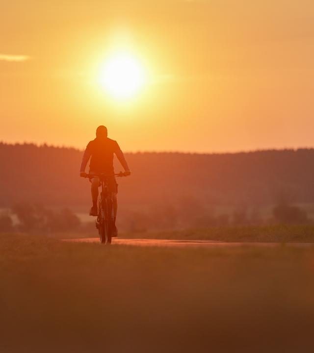 Ein Radfahrer ist am Morgen im Sonnenaufgang in Riedlingen, Baden-Württemberg, unterwegs.