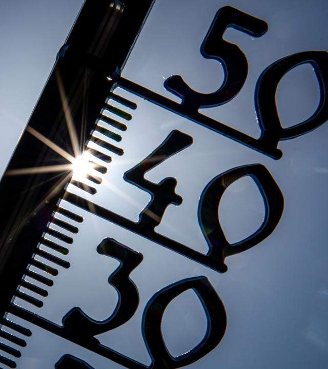 Vor einem wolkenlosen blauen Himmel zeigt ein Außenthermometer in einem Garten bereits am Vormittag über 30 Grad Lufttemperatur an.
