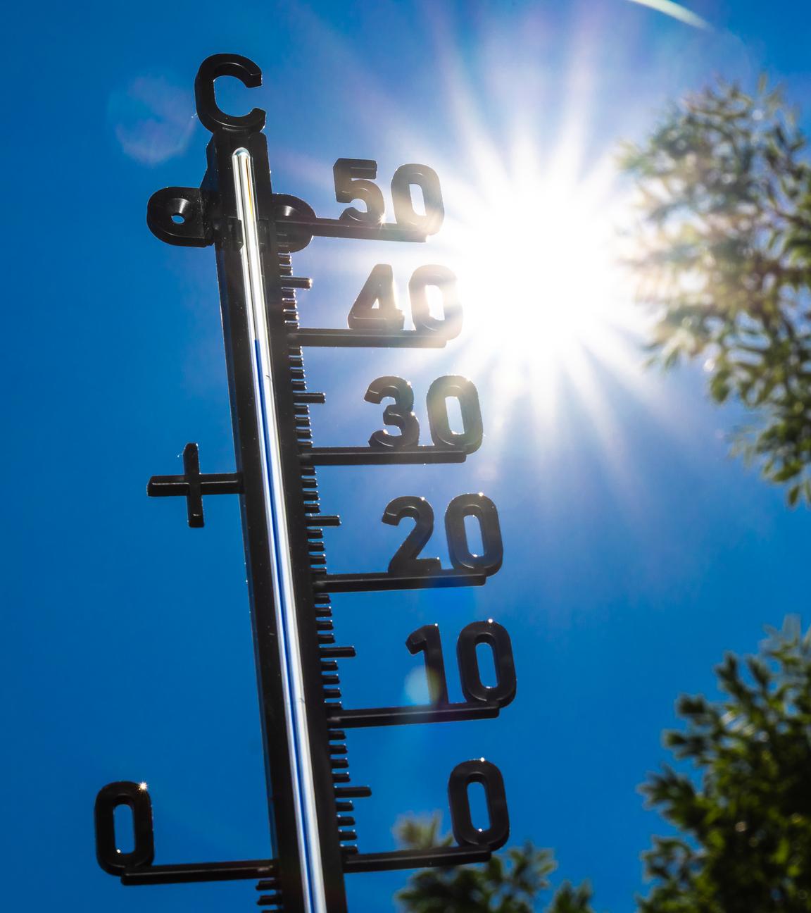 Ein Thermometer zeigt fast 40 Grad an. Im Hintergrund sind die Sonne und blauer Himmel zu sehen.