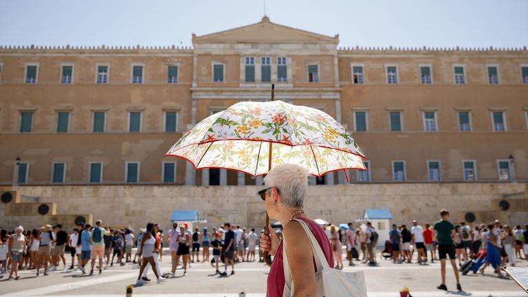 Athen: Eine Frau geht mit einem Regenschirm vor dem griechischen Parlament im Zentrum Athens spazieren.