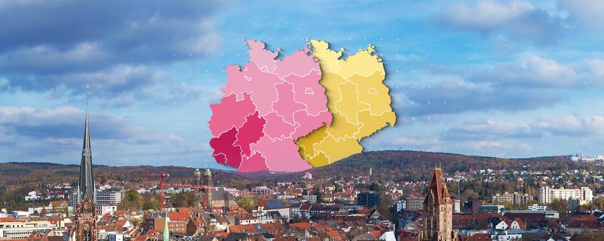Über den Dächern einer Stadt sind zwei verschiedenfarbige Grafiken einer Deutschlandkarte abgebildet.