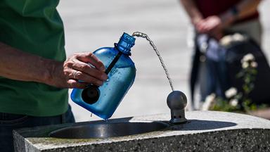 Ein Mann nutzt auf dem Gendarmenmarkt einen Wasserspender, um seine Trinkflasche aufzufüllen.