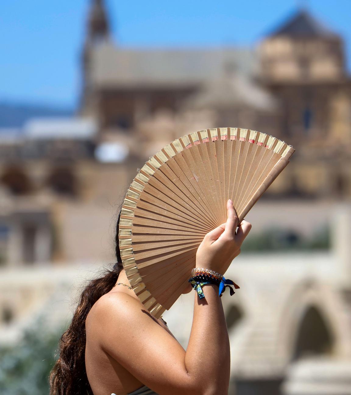 Eine Frau schützt sich mit einem Fächer vor der Sonne während einer Hitzewelle in Córdoba, Spanien, am 06.08.2025.