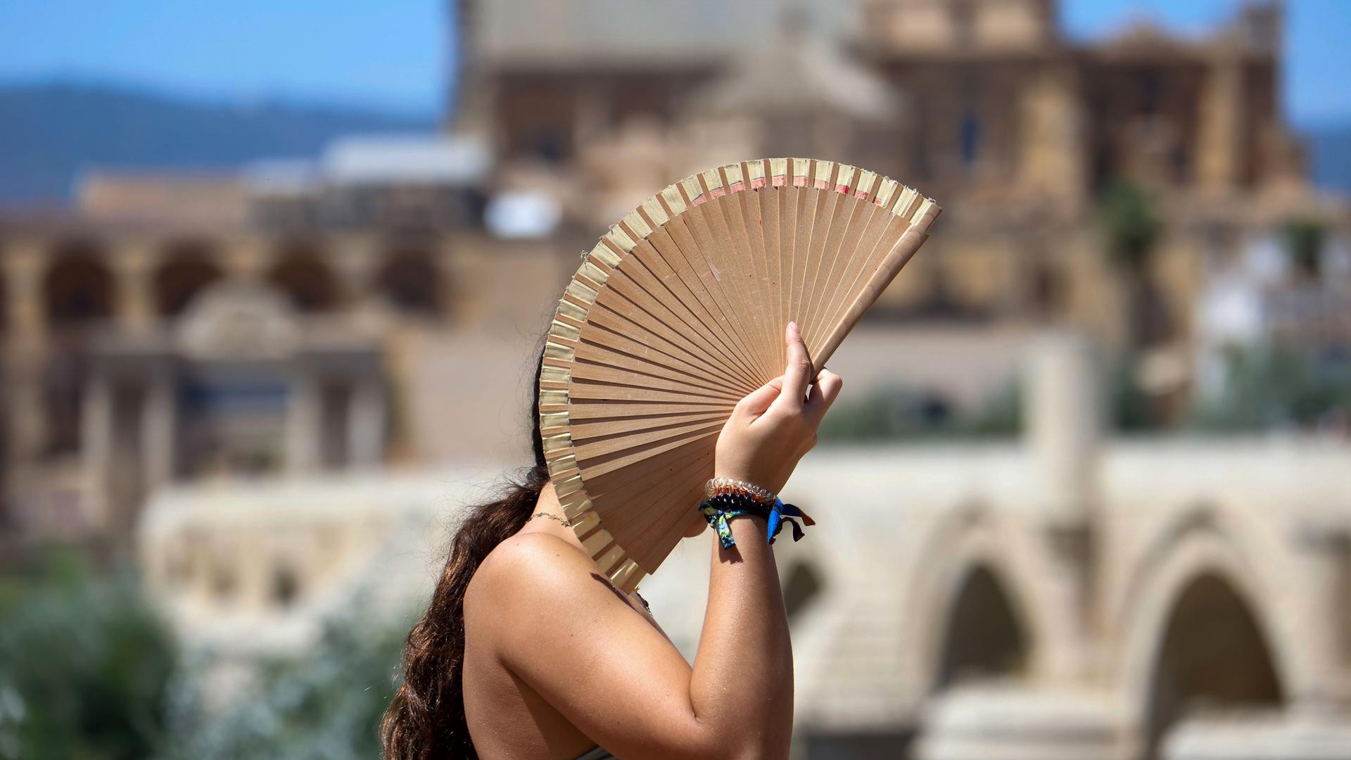 Eine Frau schützt sich mit einem Fächer vor der Sonne während einer Hitzewelle in Córdoba, Spanien, am 06.08.2025.