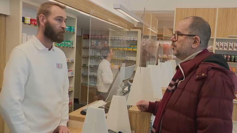Kauf von PreP in Apotheke, Apotheker steht an Thresen, Kunde mit dunkelroter Jacke und Brille dahinter.