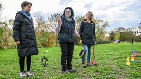 La entrenadora de perros Barbara Gerlinger (M) sostiene una correa y explica el hobby dogging a los participantes del curso, realizado el 31 de octubre de 2025.
