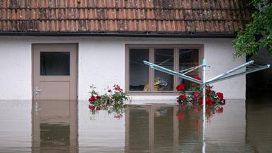 Ein Wäscheständer steht in einem überfluteten Garten von einem Wohnhaus