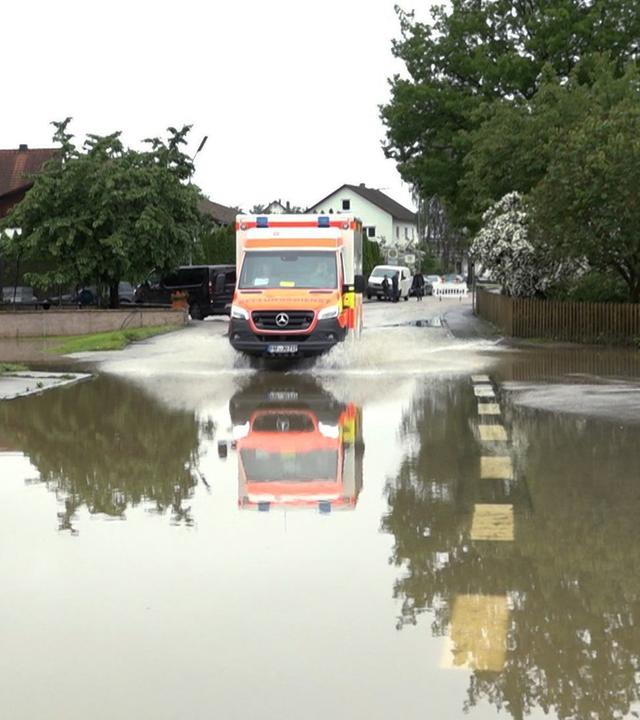 Bayern, Pfaffenhofen an der Ilm: Ein Krankenwagen fährt über eine überschwemmte Straße in Pfaffenhofen an der Ilm.