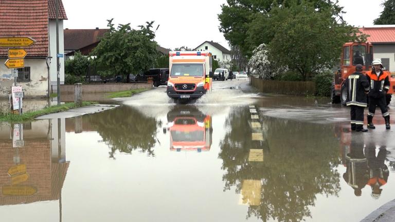 Bayern, Pfaffenhofen an der Ilm: Ein Krankenwagen fährt über eine überschwemmte Straße in Pfaffenhofen an der Ilm.