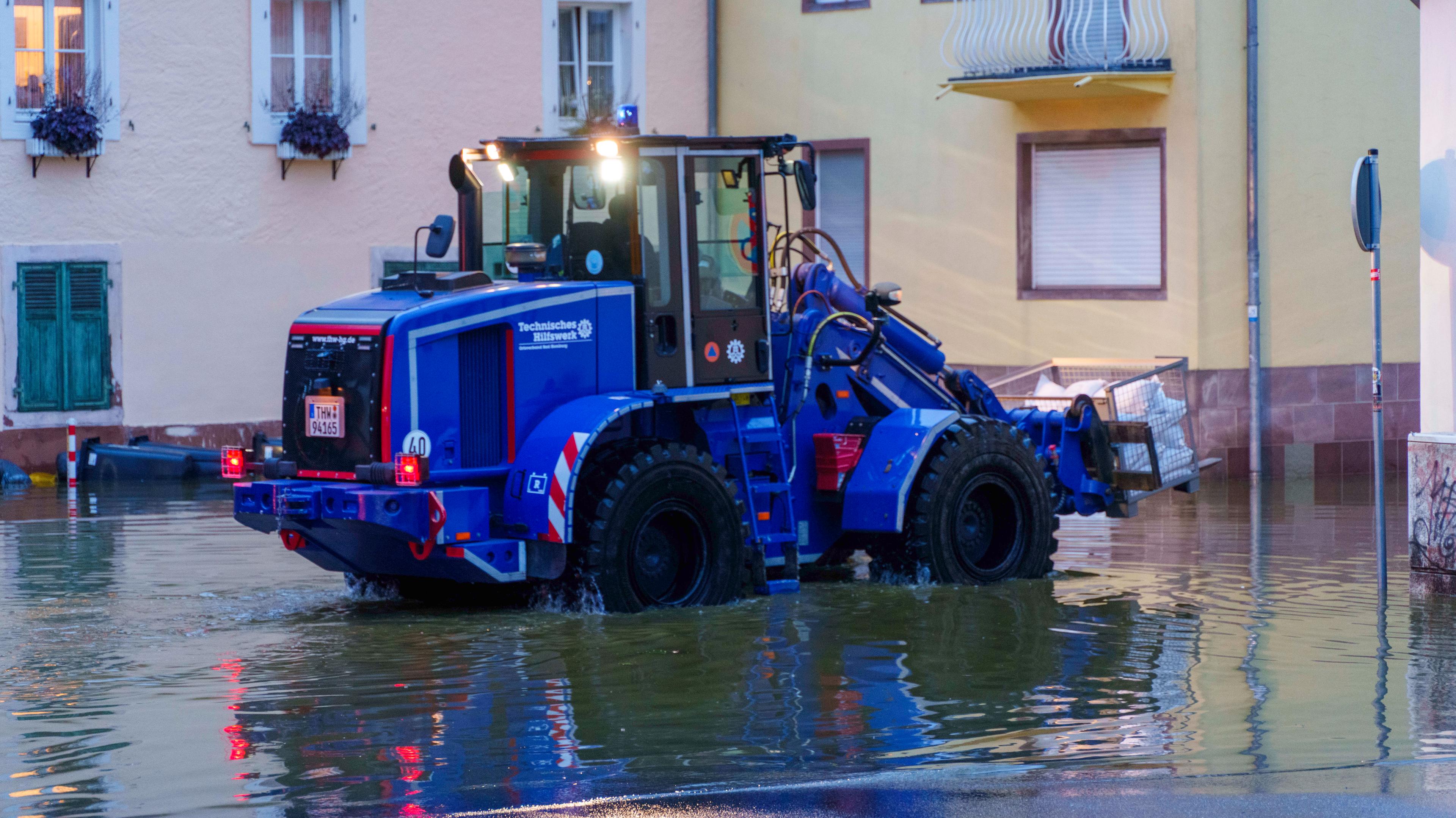 Ein Bagger des THW transportiert in der Innenstadt von Blieskastel Sandsäcke.