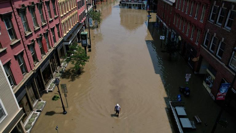 Ein Mann geht eine Straße entlang, die durch die jüngsten Regenstürme in Montpelier, Vermont, USA, überflutet wurde.