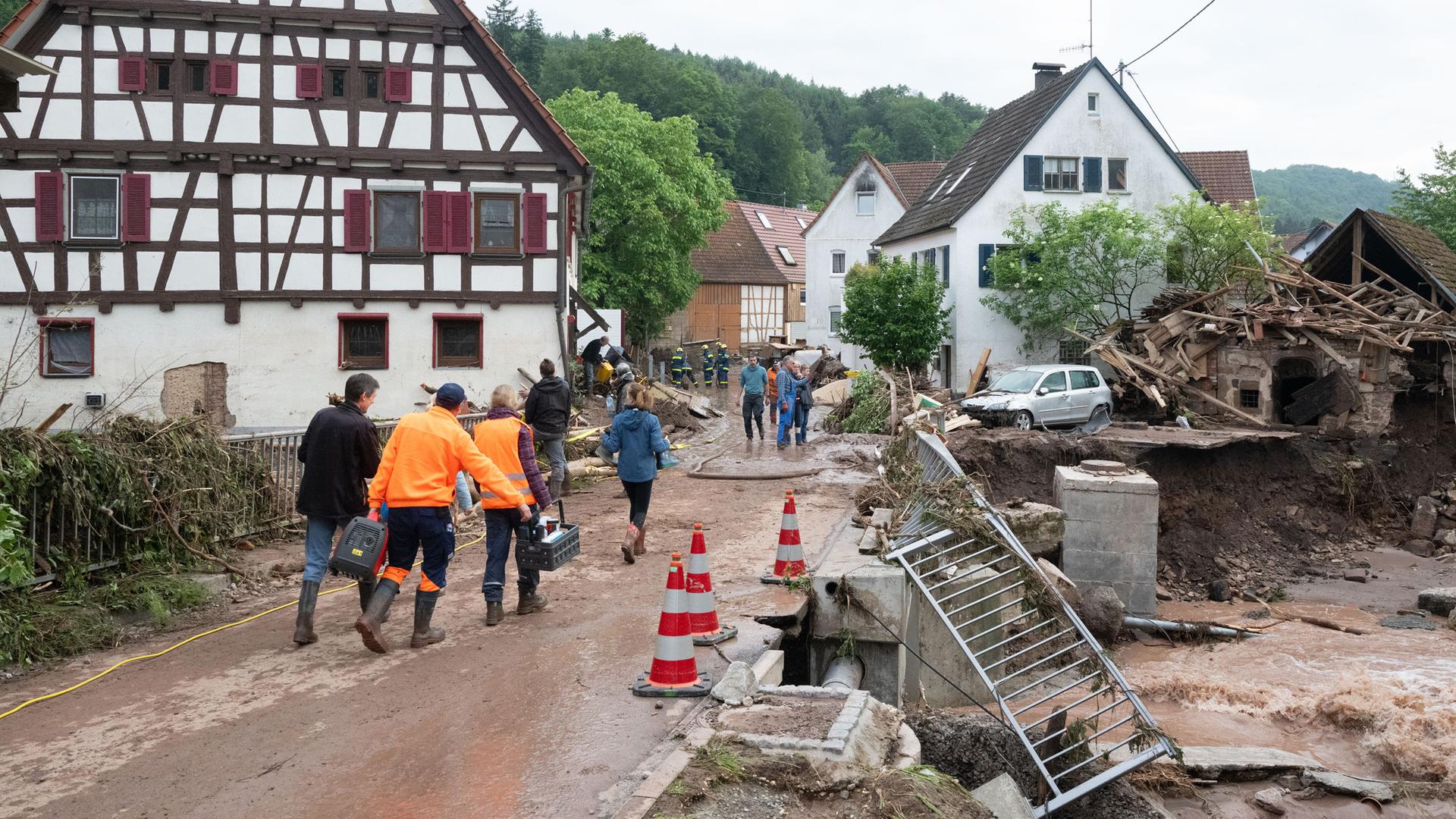 Menschen laufen in den Ort Klaffenbach nachdem ein Hochwasser starke Schäden im Ort angerichtet hat. Aufgenommen am 03.06.2024