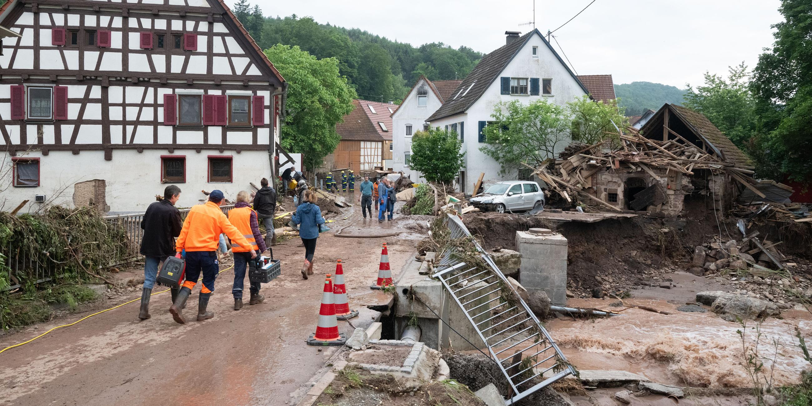 Menschen laufen in den Ort Klaffenbach nachdem ein Hochwasser starke Schäden im Ort angerichtet hat. Aufgenommen am 03.06.2024