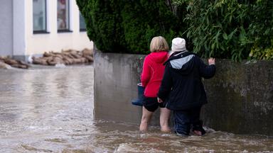 Zwei Frauen gehen durch überflutete Straßen