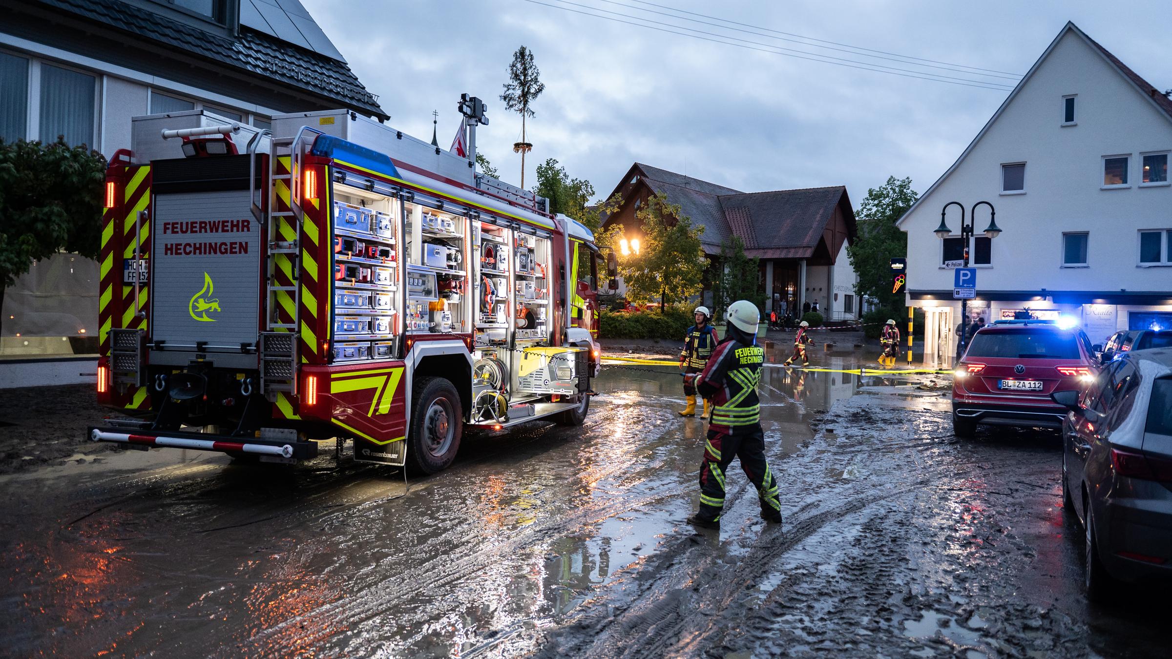 Auf einer in Matsch und Wasser bedeckten Straße steht ein Geuerwehrauto.