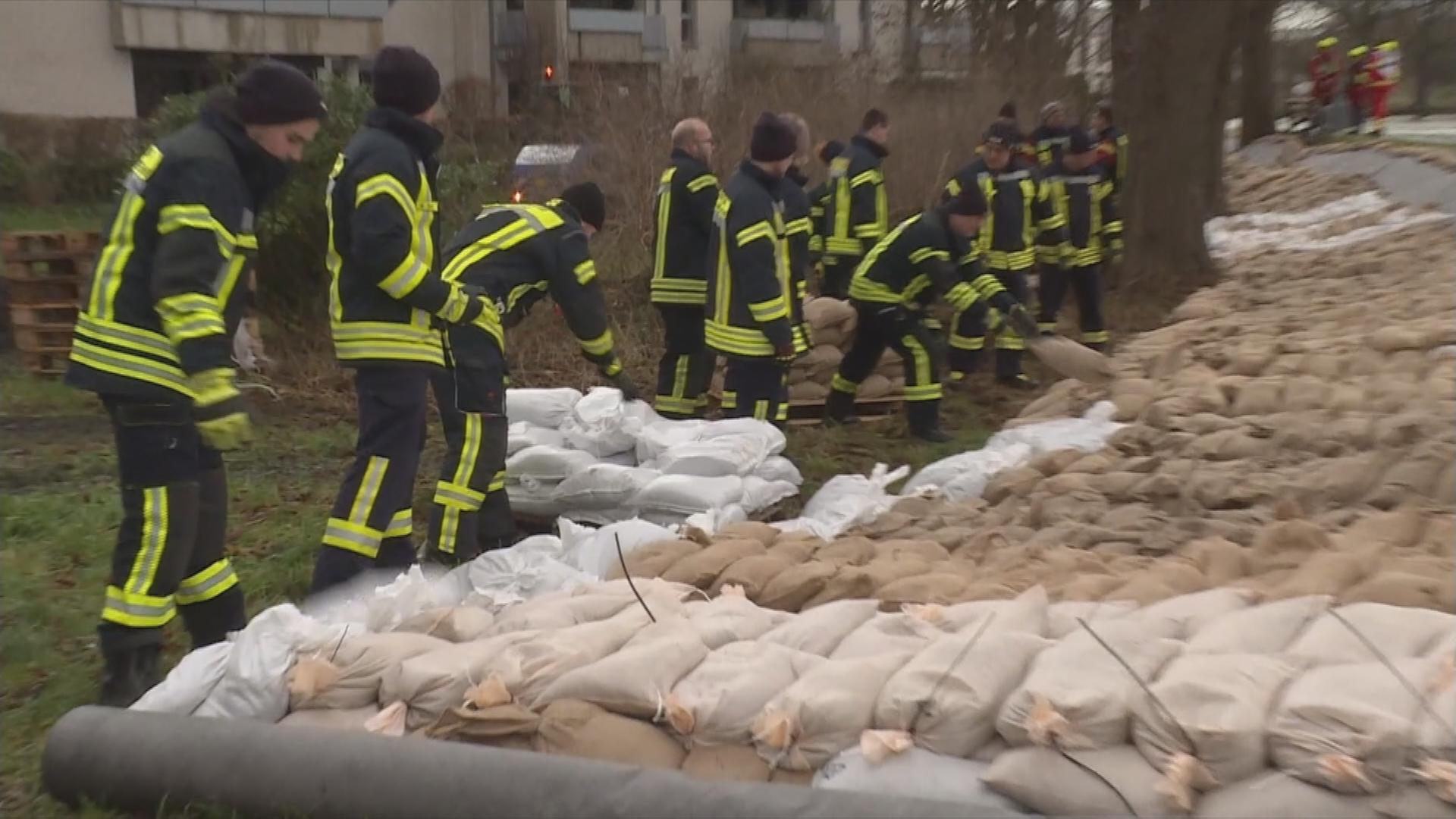 Auf dem Bild sieht man wie Feuerwehrmänner das Hochwasser mit Säcken stoppen wollen.
