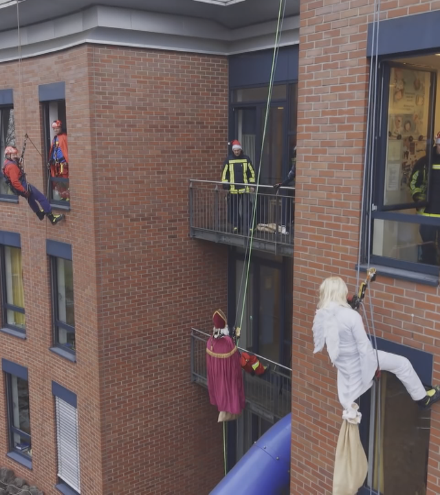Höhenretter der Feuerwehr seilen sich als Nikolaus und Engel verkleidet an der Fassade der Kinderklinik Bochum ab.
