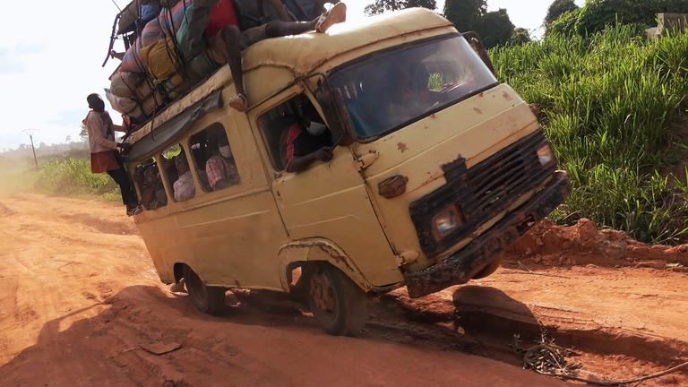 Ein weißer Laster mit Passagieren ist auf einer Straße in Schieflage geraten.