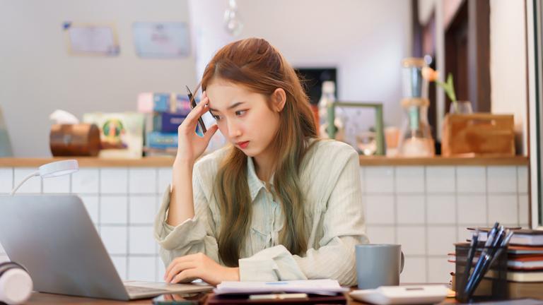 Frau arbeitet im Homeoffice an einem sibernen Laptop. 