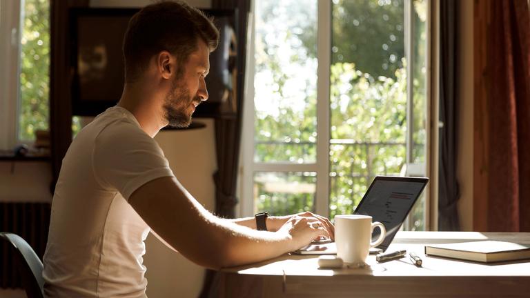 Ein Mann arbeitet zu Hause bei natürlichem Licht an einem Laptop