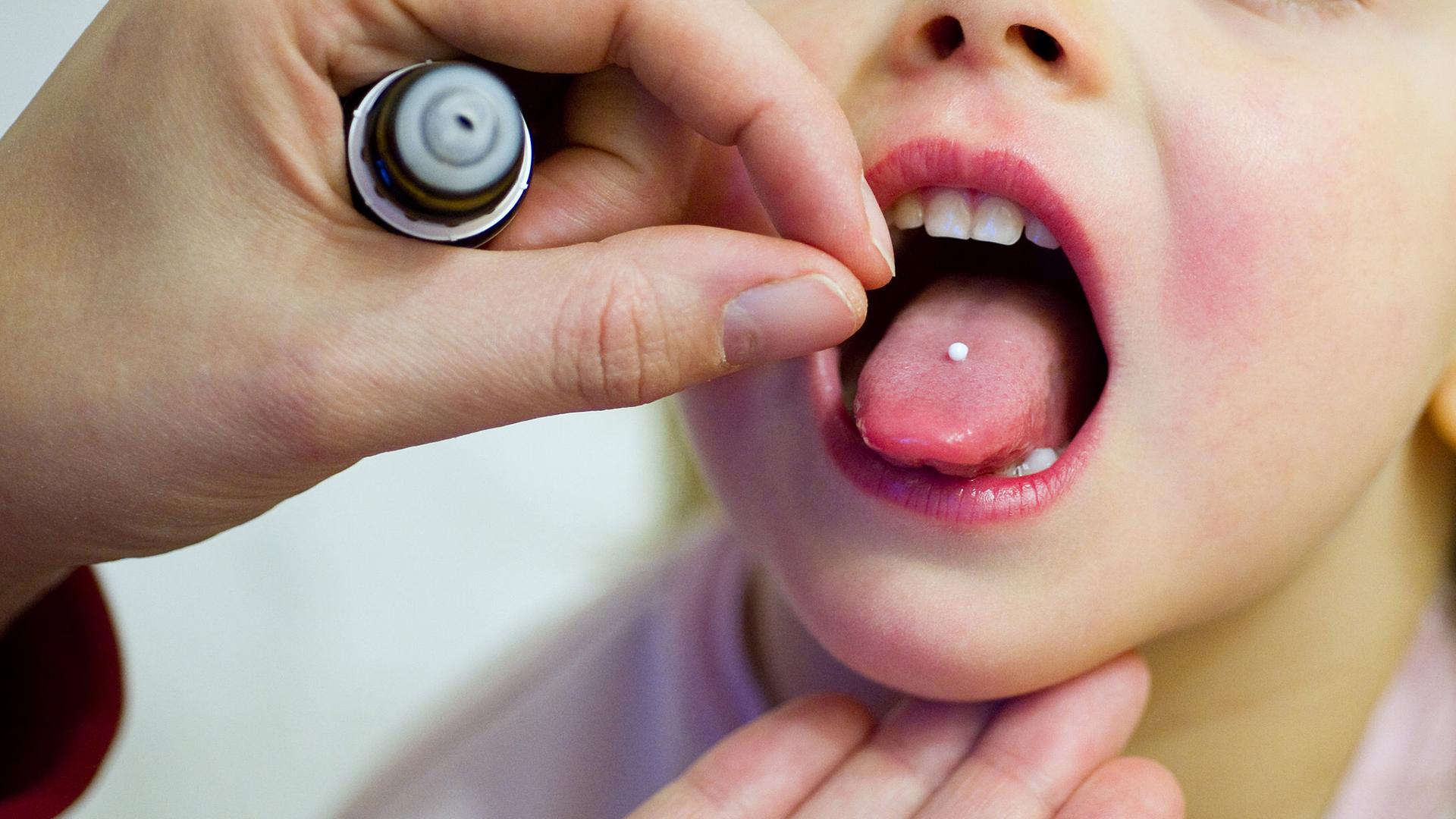 Archiv: Eine Mutter gibt ihrer erkälteten dreijährigen Tochter ein homöopathisches Mittel.