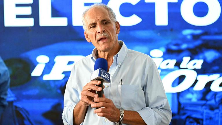 Nasry As-Fura spricht auf einer Bühne vor blauem Hintergrund.