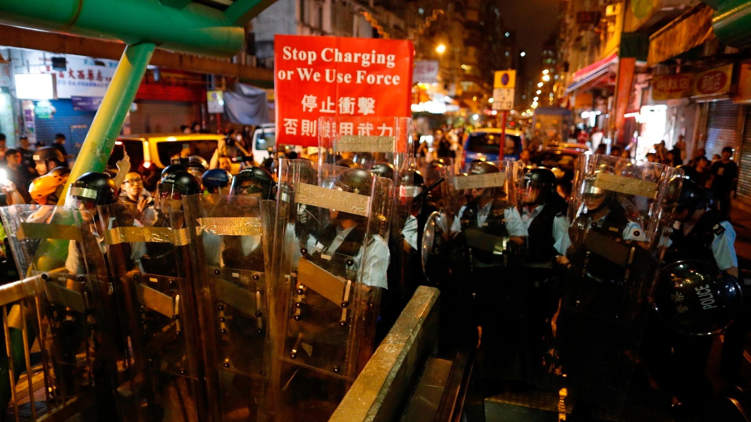 Polizisten mit Schutzschildern bei einer Polizeistation am 14.08.2019 in Hongkong.