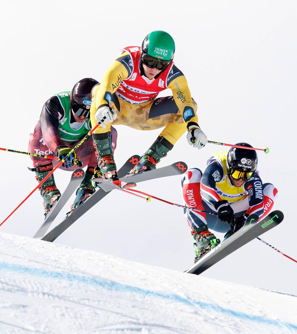 Der kanadische Freestyle-Skier Reece Howden, der deutsche Freestyle-Skier Florian Wilmsmann und der französische Freestyle-Skier Melvin Tchiknavorian springen vom Hügel ab