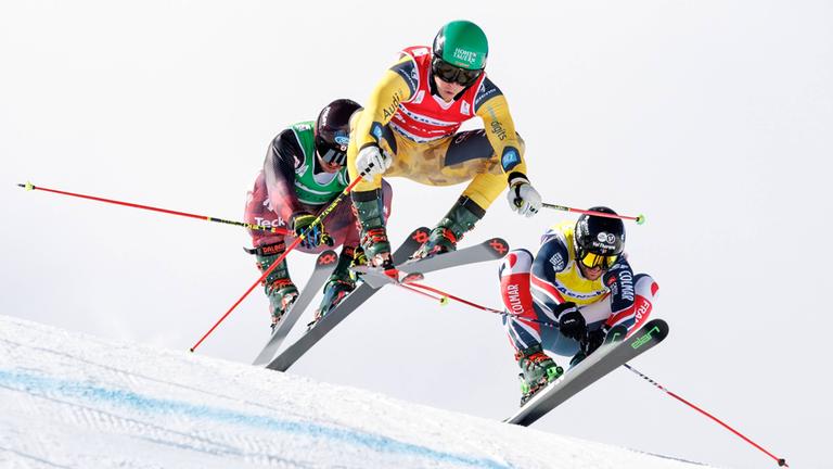 Der kanadische Freestyle-Skier Reece Howden, der deutsche Freestyle-Skier Florian Wilmsmann und der französische Freestyle-Skier Melvin Tchiknavorian springen vom Hügel ab