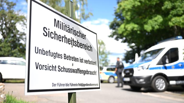  Polizisten sperren im Ortsteil Bahren eine Straße ab, während im Vordergrund ein Schild mit der Aufschrift Militärischer Sicherheitsbereich steht.