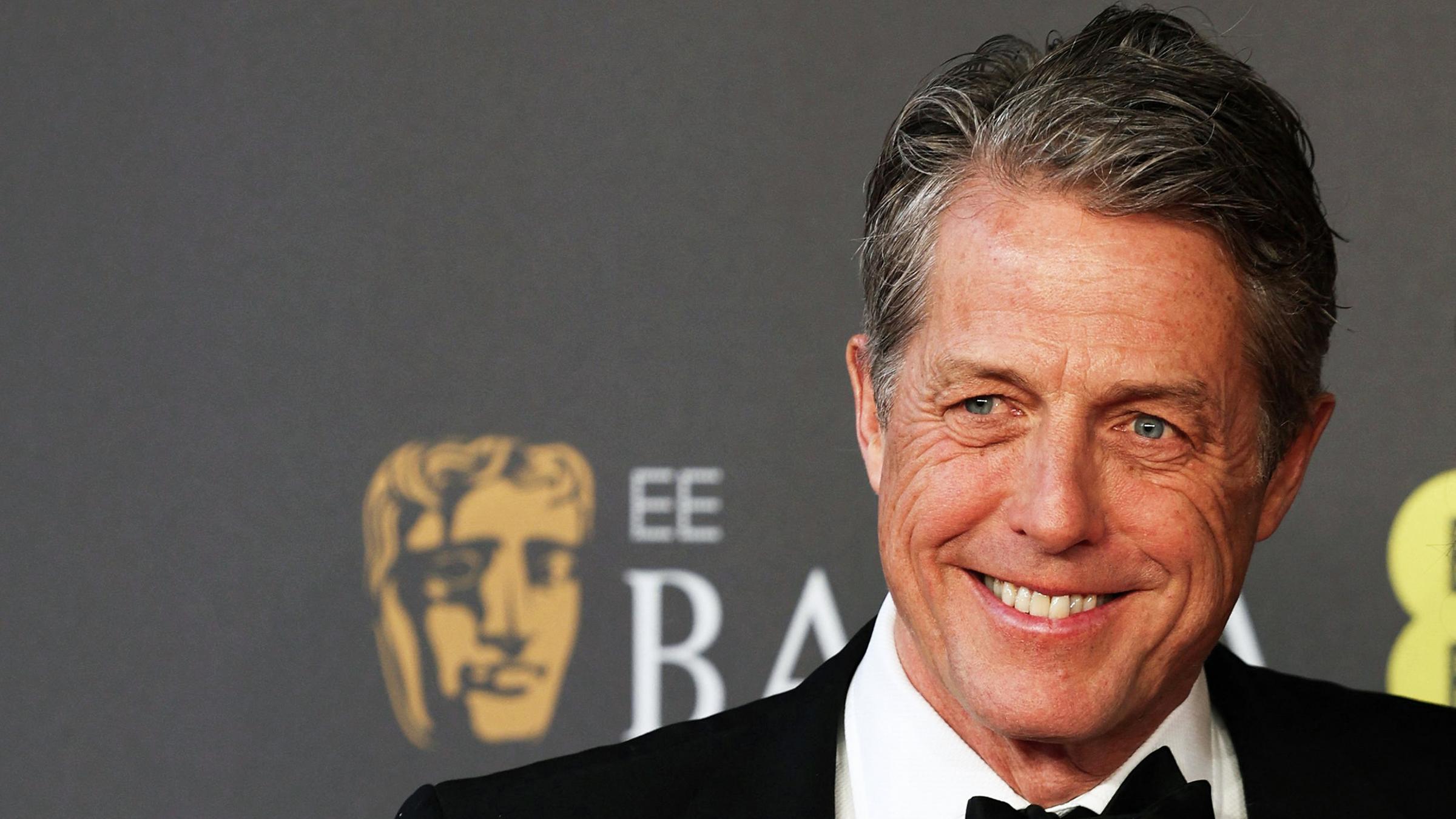 Hugh Grant, wie er grinsend in die Kamera schaut