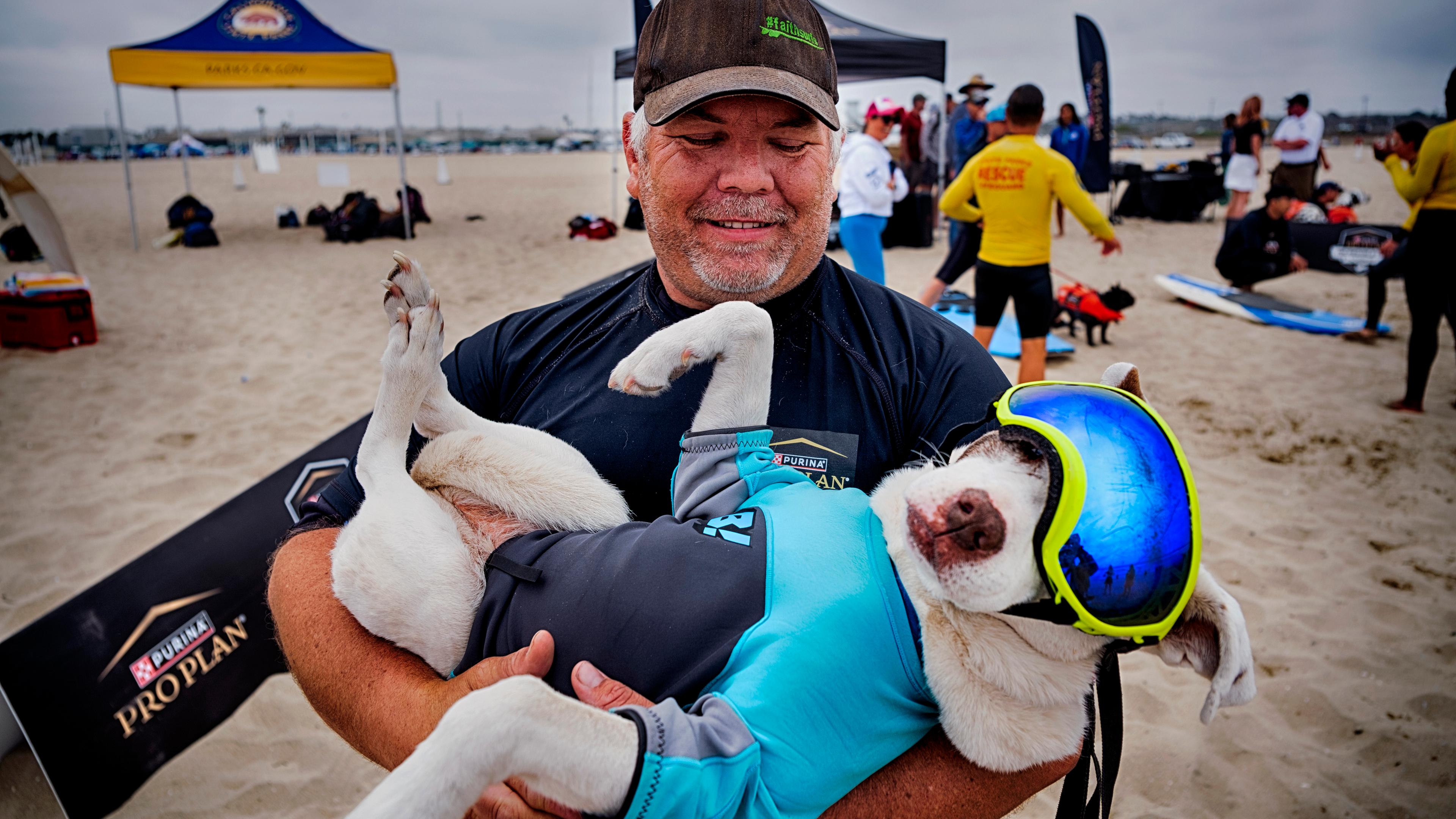 James Will nimmt sich einen Moment Zeit für Faith, einen 13-jährigen, teilweise blinden und tauben amerikanischen Pitbull-Terrier, bevor er am jährlichen regionalen Surf-Wettbewerb "Incredible Dog Challenge" am 20.06.2025 in Huntington Beach, Kalifornien, teilnimmt.