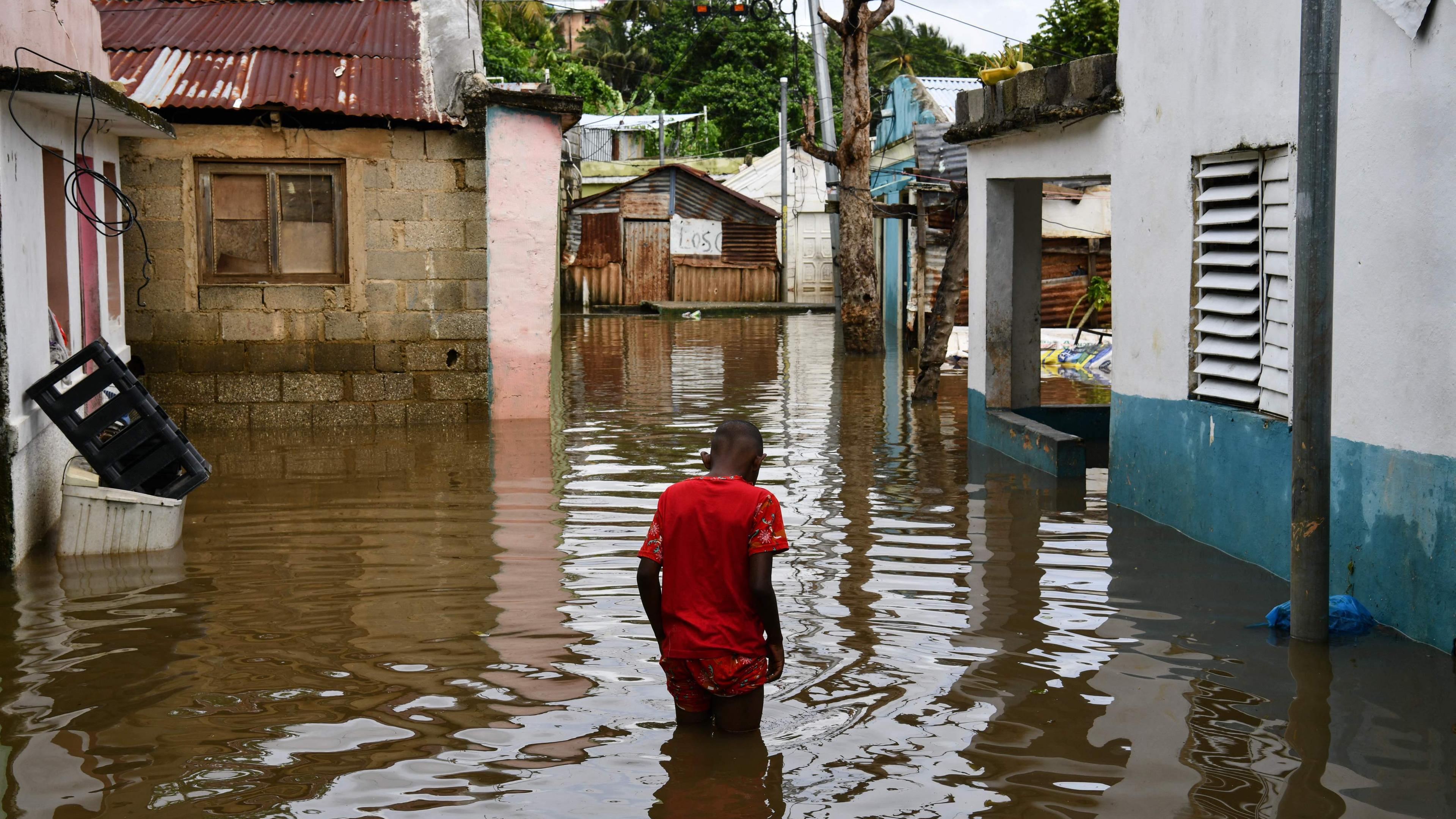 Ein Mann watet in Santo Domingo, Dominikanische Republik, durch eine überflutete Straße.