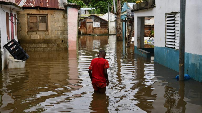 Ein Mann watet in Santo Domingo, Dominikanische Republik, durch eine überflutete Straße.
