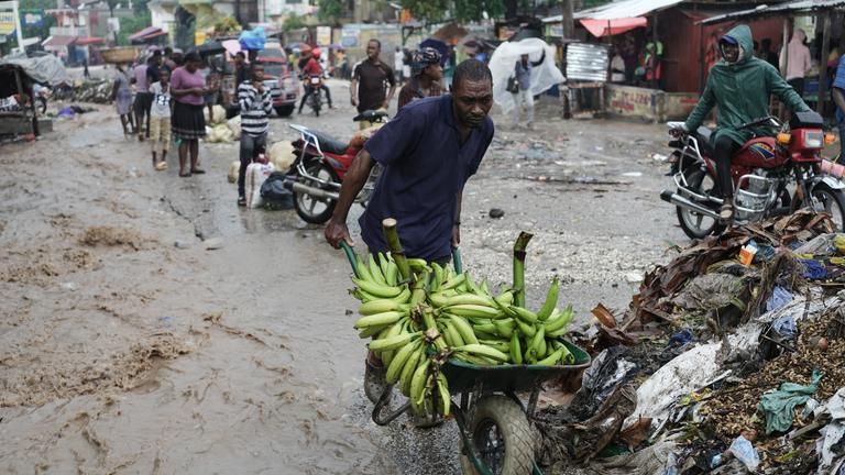 Ein Mann schiebt eine Schubkarre durch eine überflutete Straße nach dem Durchzug des Hurrikans «Melissa». 