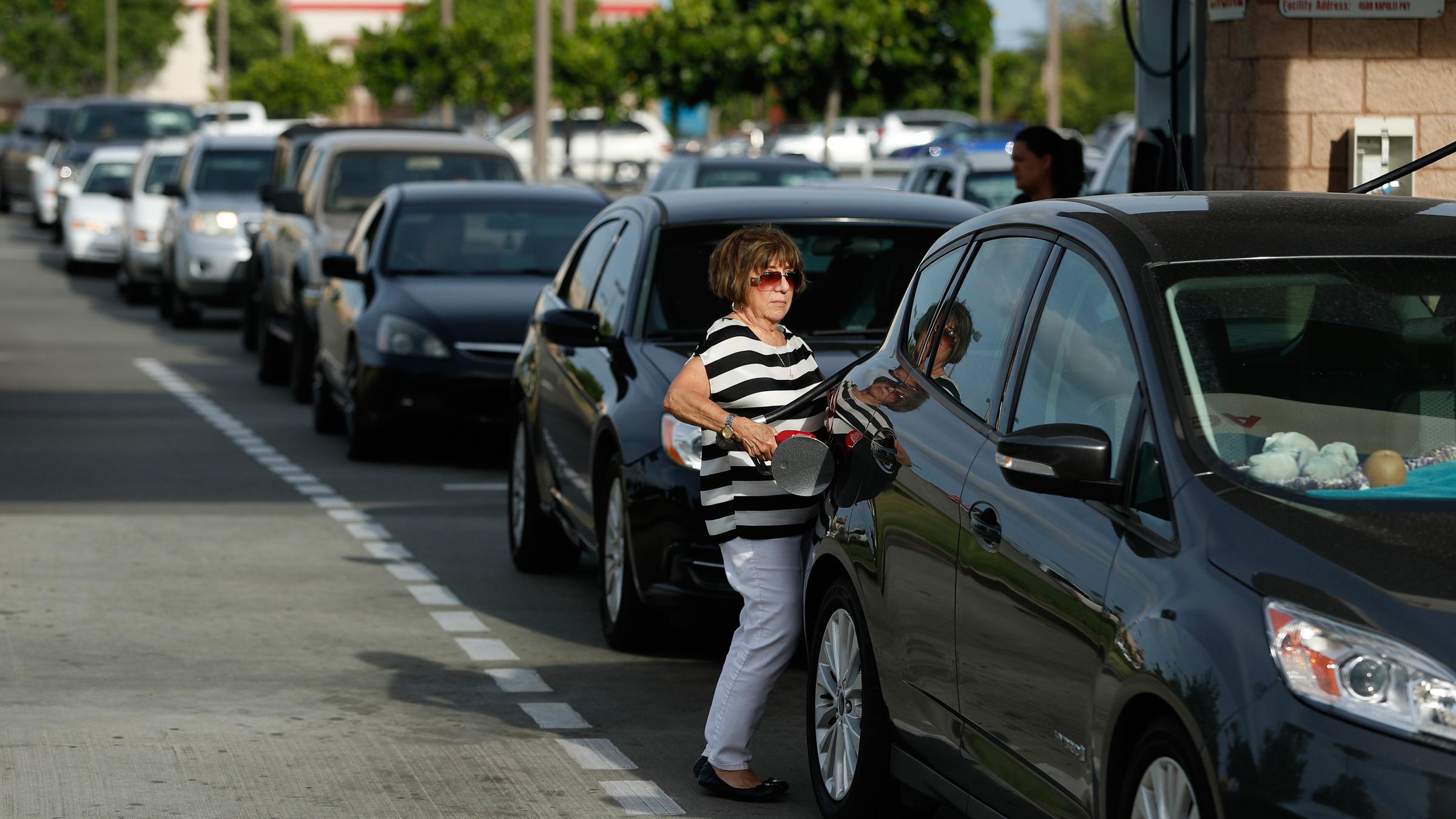 Eine Frau steht tankt ihr Wagen am 23.08.2018 in Kapolei (USA) als Vorbereitung vor dem Hurrikane Lane