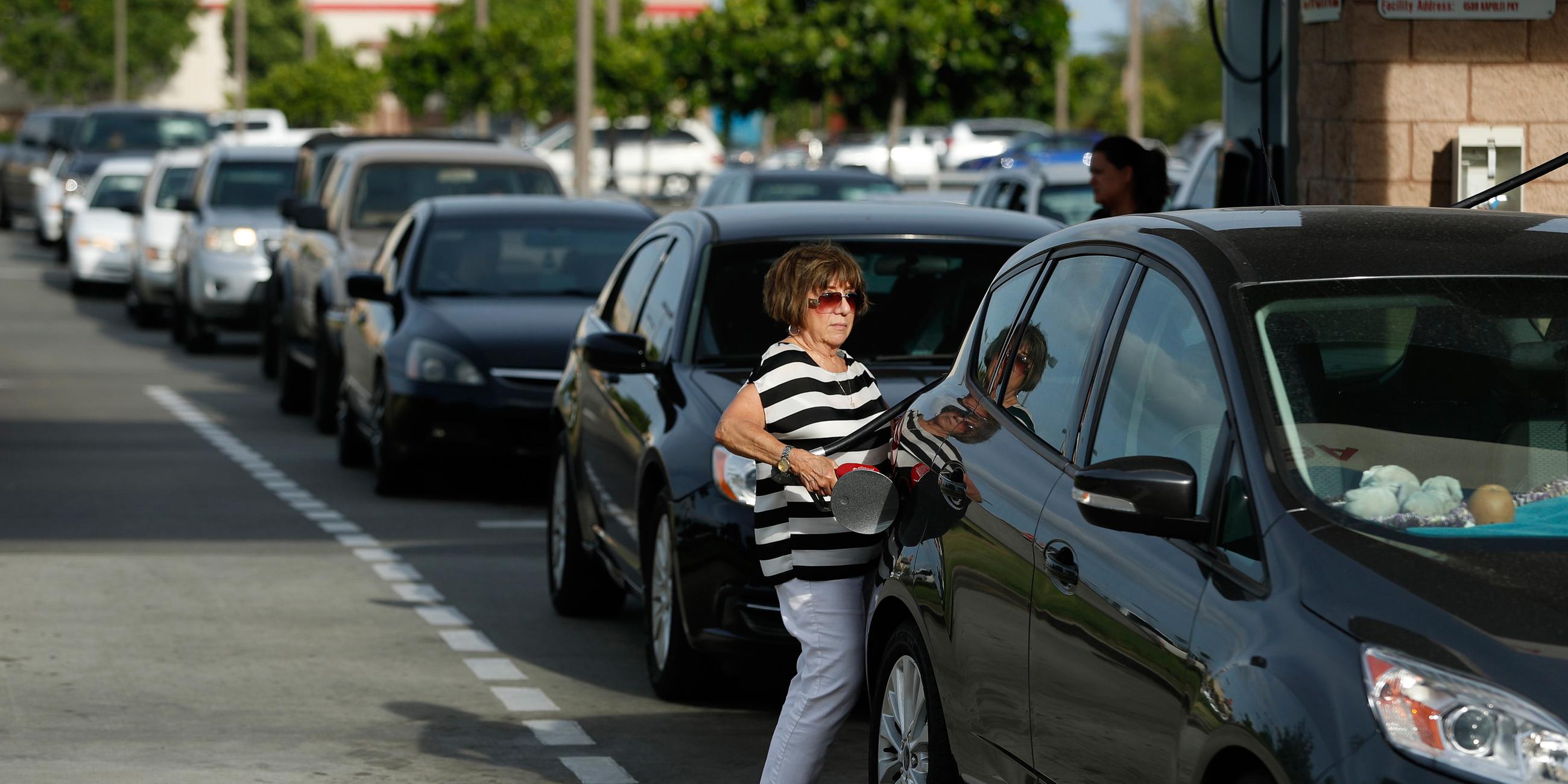 Eine Frau steht tankt ihr Wagen am 23.08.2018 in Kapolei (USA) als Vorbereitung vor dem Hurrikane Lane