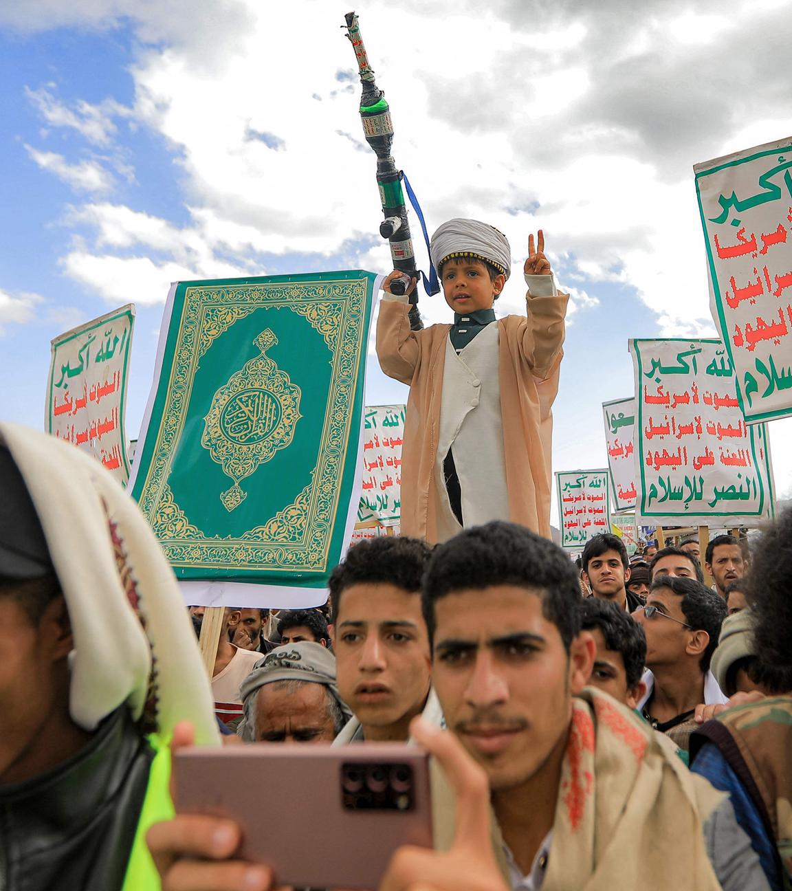 Ein Junge gestikuliert hält ein Modell eines Raketenwerfers in der Hand, während Anhänger der jemenitischen Huthis sich zu einer antiisraelischen Kundgebung versammeln. 