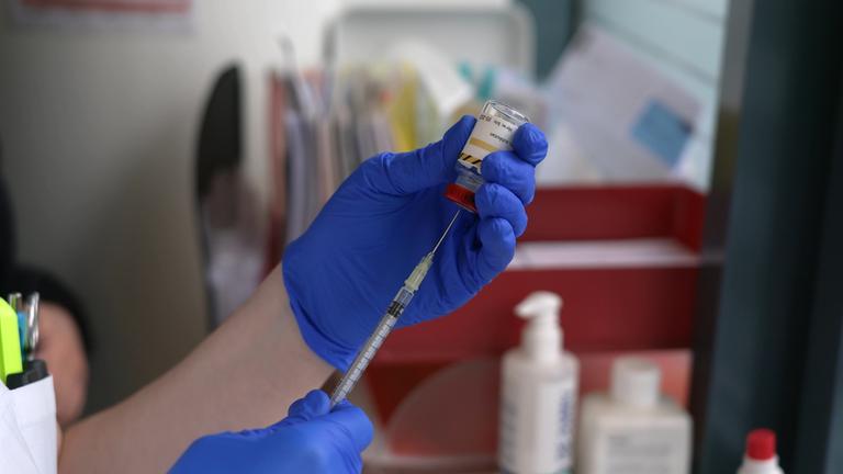 Eine Hand zieht eine Spritze für die Hyposensibilisierung aus einer Ampulle auf.