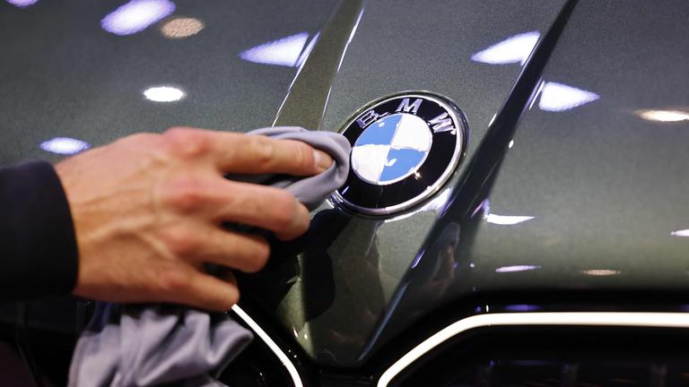 Eine Hand poliert mit einem Tuch ein Logo eines BMW-Fahrzeugs auf der Auto-Messe IAA.