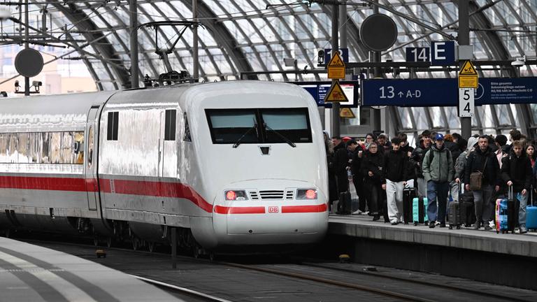 Ein ICE steht auf einem Gleis im Berliner Hauptbahnhof. Der Bahnsteig dahinter ist gefüllt mit Reisenden.