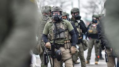 Bundesbeamte stehen Wache, während sich am 8. Januar 2026 Demonstrierende vor dem Bishop Henry Whipple Federal Building in Saint Paul, Minnesota, versammeln.