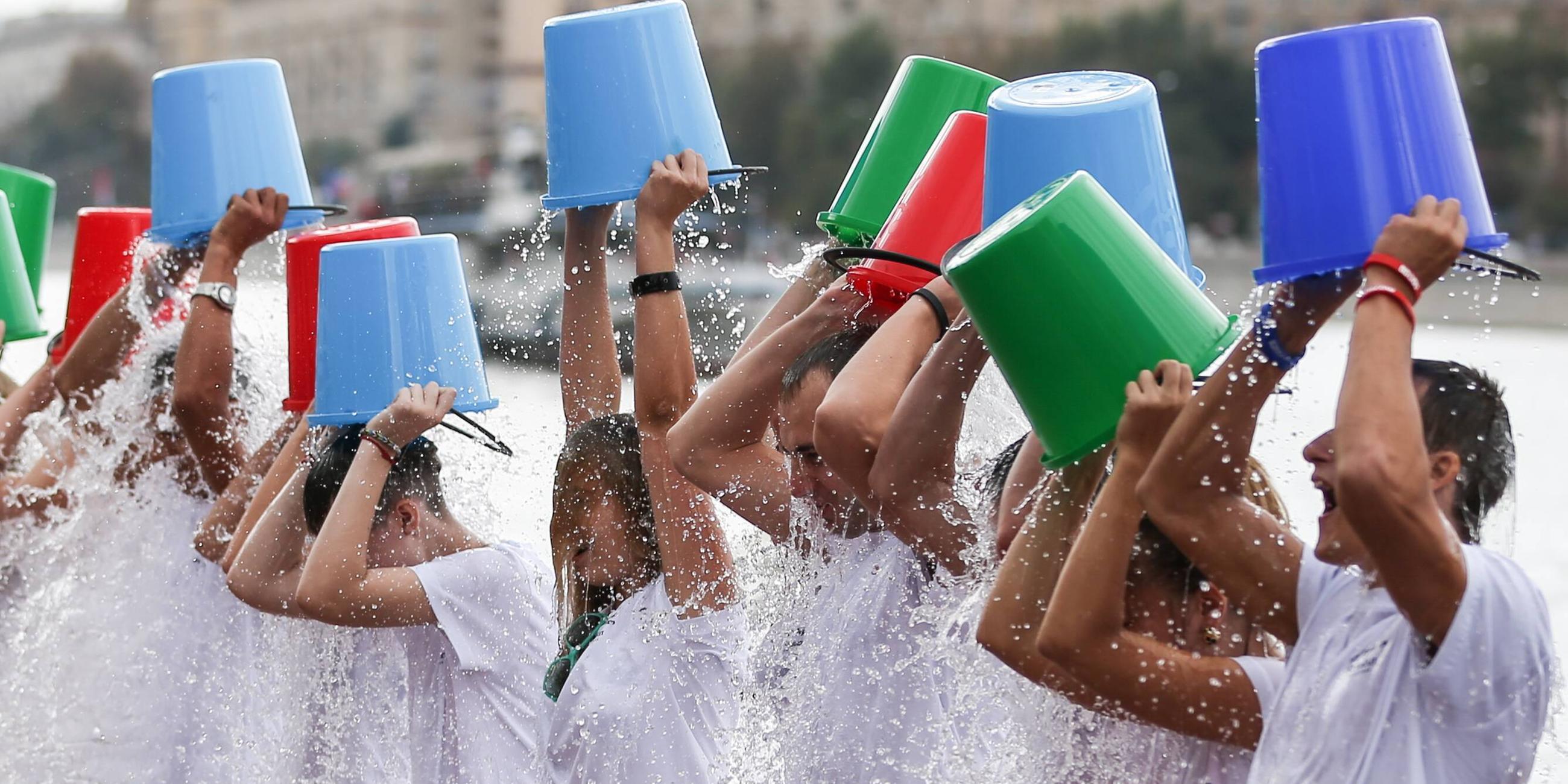 Das Bild zeigt viele Menschen, die sich einen Eimer mit Eiswasser über den Kopf schütten.