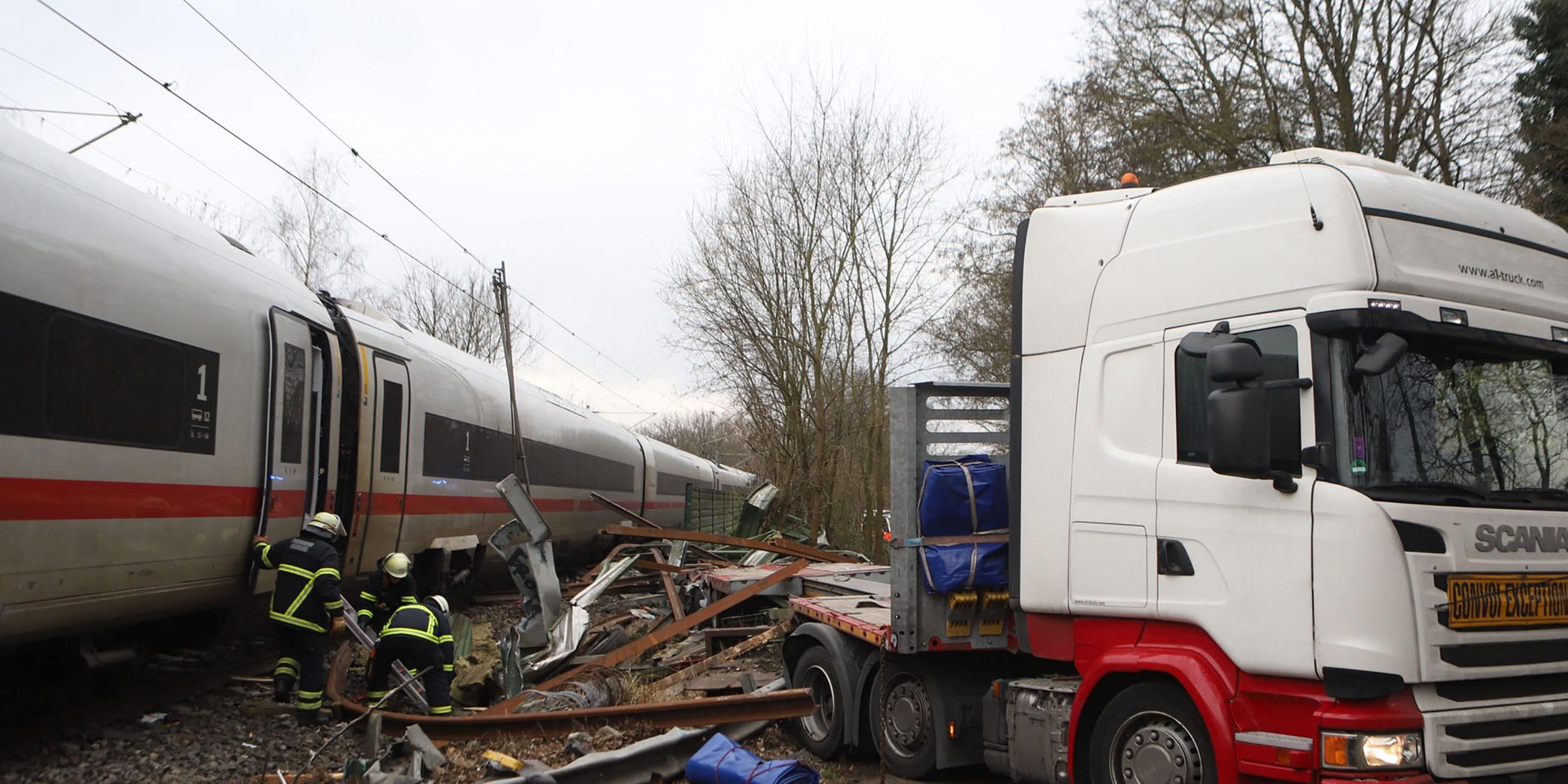 Ein Polizist sieht zu, wie Feuerwehrleute an der Unfallstelle zwischen einem LKW und einem ICE (InterCity Express) der Deutschen Bahn an einem Bahnübergang im Hamburger Stadtteil Rönneburg arbeiten