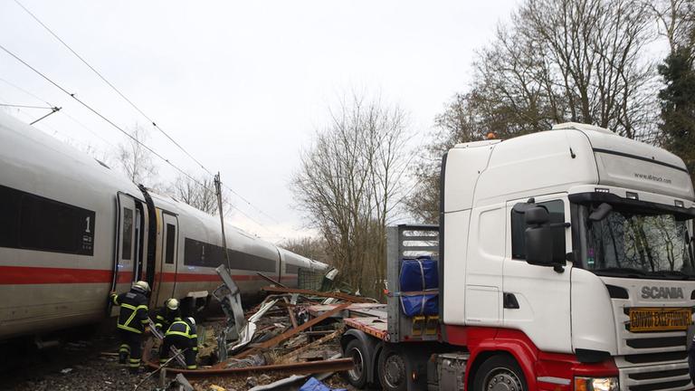 Ein Polizist sieht zu, wie Feuerwehrleute an der Unfallstelle zwischen einem LKW und einem ICE (InterCity Express) der Deutschen Bahn an einem Bahnübergang im Hamburger Stadtteil Rönneburg arbeiten