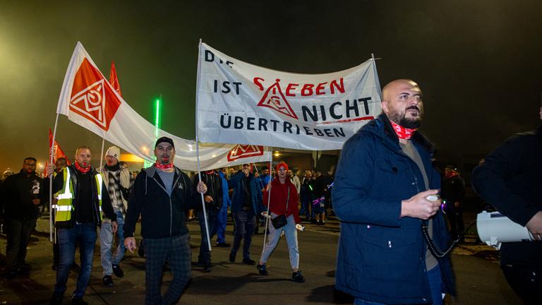 Mitarbeiter der ZF Friedrichshafen AG demonstrieren mit Fahnen und Fackeln vor dem Werk.
