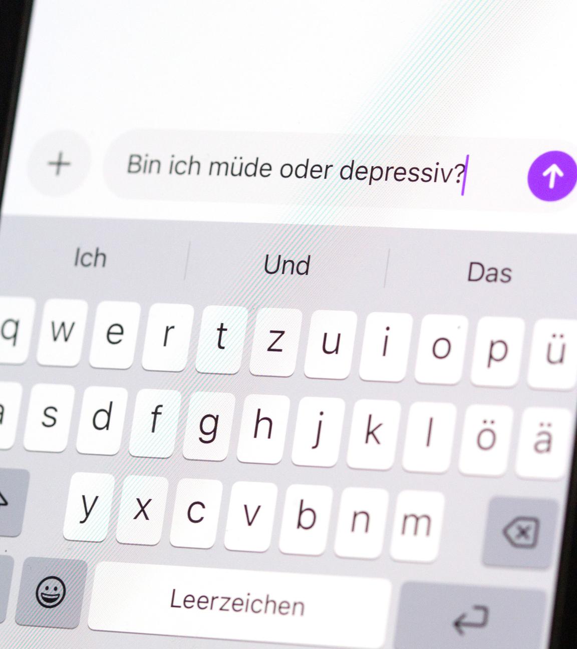 Eine Person hält ein Smartphone in der Hand, auf dem eine Suchanfrage mit der Frage «Bin ich müde oder depressiv?» in einem KI-Chatfenster zu sehen ist. 